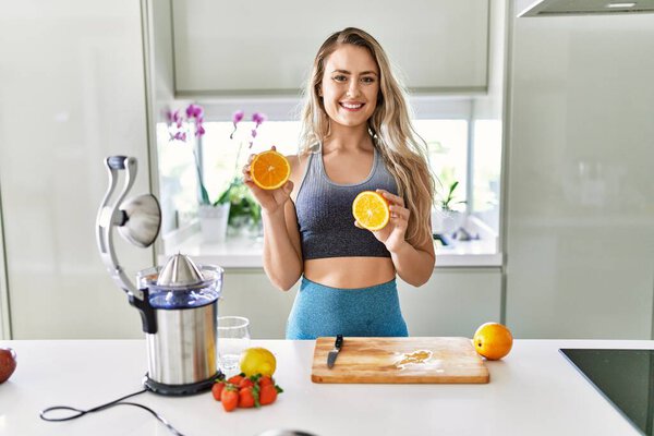 Young woman smiling confident holding orange at kitchen