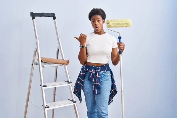 Africano Americano Mulher Segurando Pintor Rolos Surpreendido Apontando Com Dedo — Fotografia de Stock