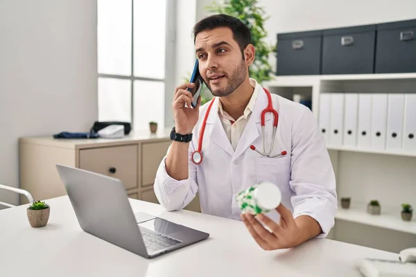 Young Hispanic Man Wearing Doctor Uniform Prescribe Pills Smartphone Clinic — Stock Photo, Image