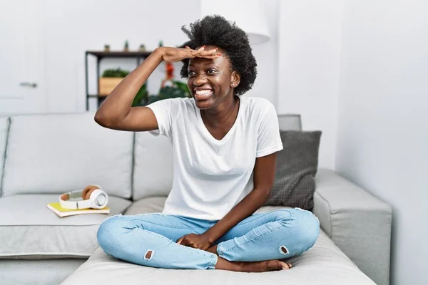 Afrikaanse Jonge Vrouw Zitten Bank Thuis Erg Blij Glimlachend Kijken — Stockfoto