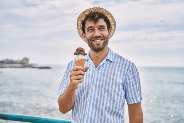 年轻的惊慌失措的男人在海滩上高兴地吃着冰激凌 — 图库照片