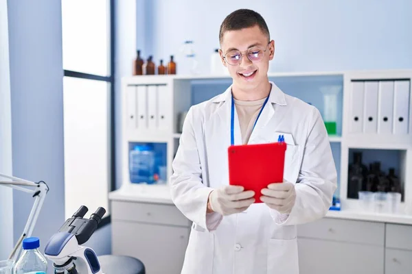 Young Hispanic Man Scientist Smiling Confident Using Touchpad Laboratory — стоковое фото