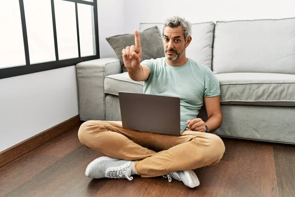Orta Yaşlı Spanyol Adam Oturma Odasında Dizüstü Bilgisayar Kullanıyor Parmağını — Stok fotoğraf