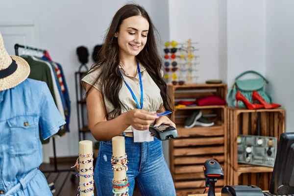 年轻的高加索女人带着自信的笑容在服装店付钱 — 图库照片