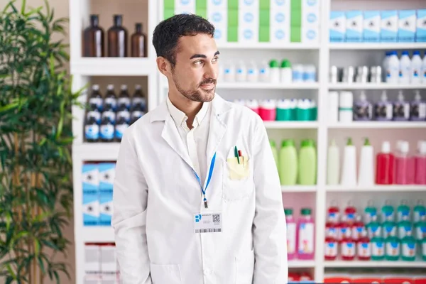 Handsome Hispanic Man Working Pharmacy Drugstore Smiling Looking Side Staring — Zdjęcie stockowe