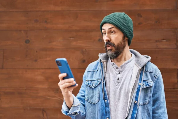 Young Hispanic Man Using Smartphone Scared Amazed Open Mouth Surprise — Stock Photo, Image