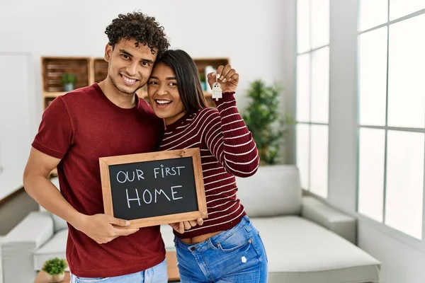 Young Latin Couple Smiling Happy Holding Our First Home Blackboard — Zdjęcie stockowe