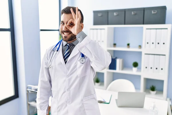 手コキヒスパニック男身に着けています医師の制服とStethoscopeで医療クリニック笑顔幸せありますOk Signとともに手で目を通して指を見て — ストック写真
