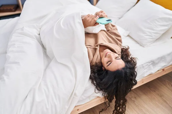 Young Hispanic Woman Using Smartphone Lying Bed Bedroom — Stockfoto