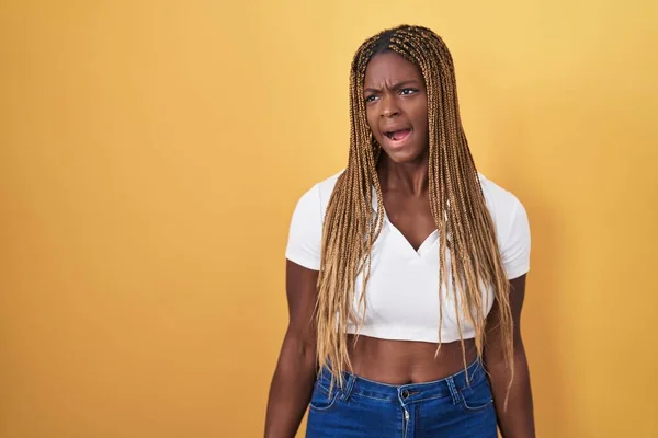 Африканская Американка Плетеными Волосами Стоящая Жёлтом Фоне Злая Безумная Кричащая — стоковое фото