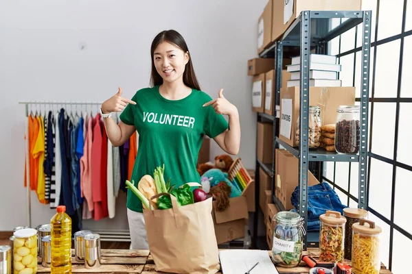 Genç Asyalı Kadın Bağış Standında Gönüllü Tişört Gösterirken Gülümsüyor — Stok fotoğraf