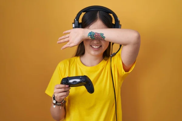 中国的年轻女子玩电子游戏时 抱着控制器笑着开开心心地玩着 用手摸着脸看了一眼 很惊讶也很兴奋 — 图库照片