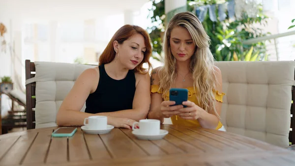 Dvě Ženy Pomocí Smartphonu Pití Kávy Sedí Stole Doma Terase — Stock fotografie