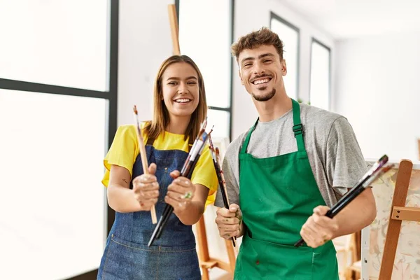 Young Hispanic Artist Couple Smiling Happy Holding Paintbrushes Art Studio — Stock Photo, Image