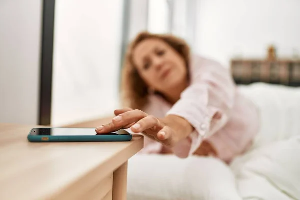 Biała Kobieta Średnim Wieku Wyłączająca Budzik Smartfona Leżąca Łóżku Sypialni — Zdjęcie stockowe