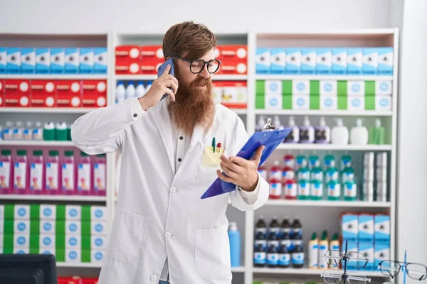 Young Redhead Man Pharmacist Talking Smartphone Reading Document Pharmacy — Stockfoto