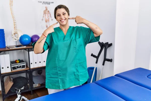 Young Hispanic Woman Wearing Physiotherapist Uniform Standing Clinic Smiling Cheerful — Stockfoto