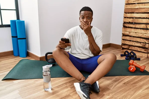 Young African Man Sitting Training Mat Gym Using Smartphone Shocked — Stok fotoğraf