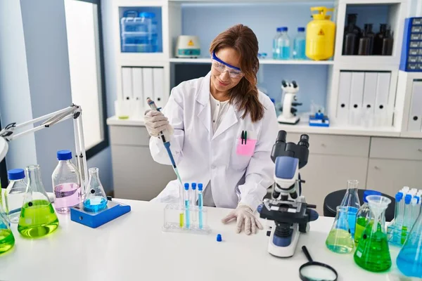 研究室で働いているピペットを使って科学者の制服を着た若いラテン語の女性 — ストック写真