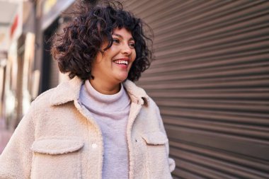 Young beautiful hispanic woman smiling confident looking to the side at street