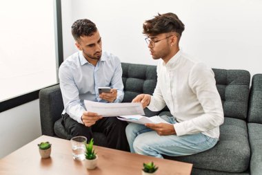 Two hispanic men business workers reading document working at office