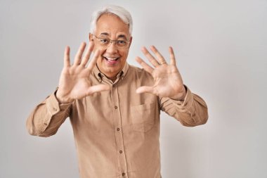 İspanyol kıdemli gözlüklü adam 10 numarayı gösterip işaret ederken kendinden emin ve mutlu gülümsüyor.. 