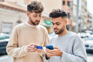 Young couple using smartphone and credit card standing together at street