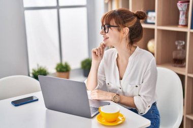 Young woman using laptop sitting on table at home