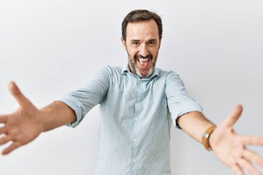 Arka planda sakallı, orta yaşlı İspanyol bir adam kameraya sarılıp gülümsüyor. Mutluluğu kucaklayan neşeli bir ifade.. 