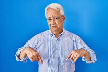 Gözlüklü son sınıf öğrencisi üzgün ve üzgün görünüyor, parmaklarıyla yön gösteriyor, mutsuz ve depresif. 