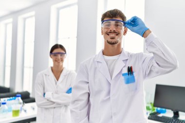 Man and woman partners wearing scientist uniform standing with arms crossed gesture at laboratory