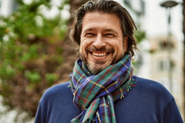 Parkta gülümseyen orta yaşlı yakışıklı adam.