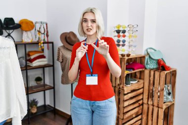 Perakende satış mağazasında yönetici olarak çalışan beyaz bir kadın tiksinti dolu bir ifade, tiksinti tepkisi yüzünden tiksinti ve korku dolu bir ifade. Eller havada. 