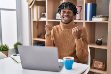 Young african man with dreadlocks working using computer laptop celebrating surprised and amazed for success with arms raised and open eyes. winner concept. 