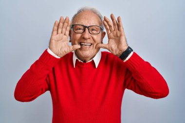 Senior man with grey hair standing over isolated background smiling cheerful playing peek a boo with hands showing face. surprised and exited 
