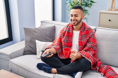 African american man drinking coffee watching tv at home