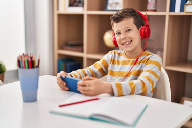 Sarışın çocuk evde akıllı telefon kullanarak video oyunu oynuyor