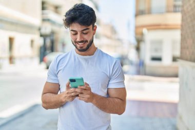Sokakta akıllı telefon kullanan, kendine güvenen genç bir İspanyol.