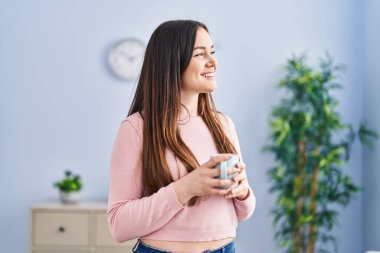 Evde kahve içen kendine güvenen genç bir kadın.