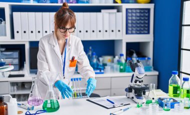 Laboratuvarda test tüpleri tutan genç bilim kadını.