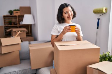 Young woman smiling confident drinking coffee at new home