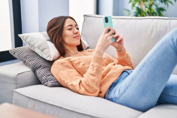 Jovem Bela Mulher Hispânica Usando Smartphone Deitado Sofá Casa — Fotografia de Stock