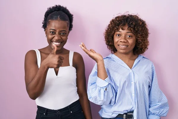 Two African Women Standing Pink Background Showing Palm Hand Doing — Stok fotoğraf