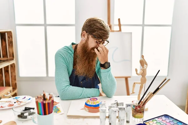 红头发的男人 留着长长的胡子 在艺术工作室里画着黏土碗 疲惫地揉揉鼻子和眼睛 感觉疲劳和头痛 压力和挫败感概念 — 图库照片