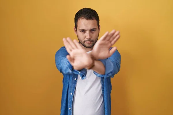 Hispanic Man Standing Yellow Background Rejection Expression Crossing Arms Palms — Stockfoto