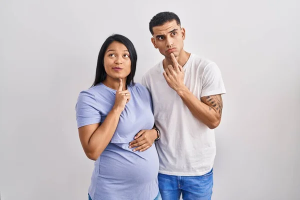Jong Hispanic Paar Verwacht Een Baby Staan Achtergrond Denken Geconcentreerd — Stockfoto