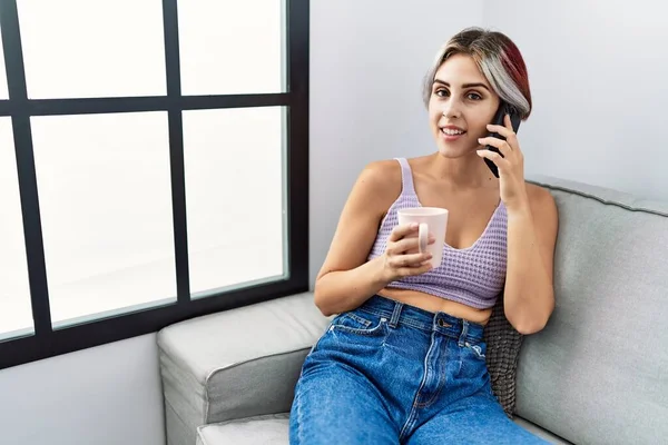 Young Caucasian Girl Drinking Coffee Talking Smartphone Sitting Sofa Home — Fotografia de Stock