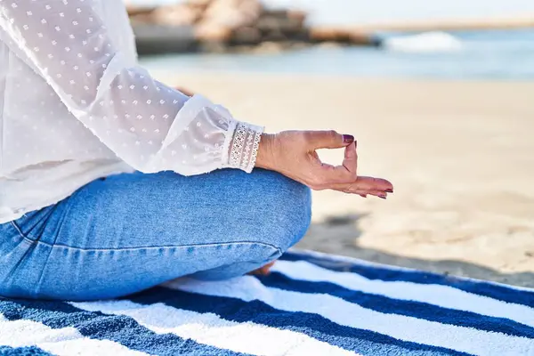 中年妇女坐在海滨的毛巾上做瑜伽运动 — 图库照片