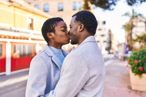 Man and woman couple hugging each other and kissing at street