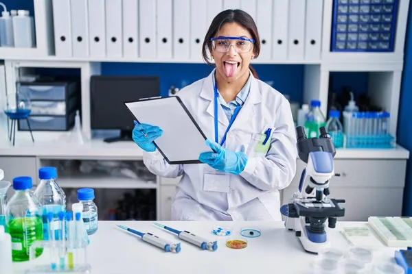 Hispanic Young Woman Working Scientist Laboratory Sticking Tongue Out Happy — ストック写真